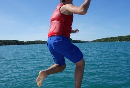 A man in a life vest jumping into Walloon Lake on a sunny day in Michigan