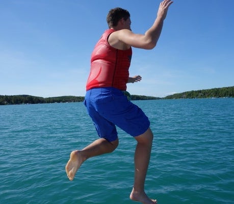 A man in a life vest jumping into Walloon Lake on a sunny day in Michigan